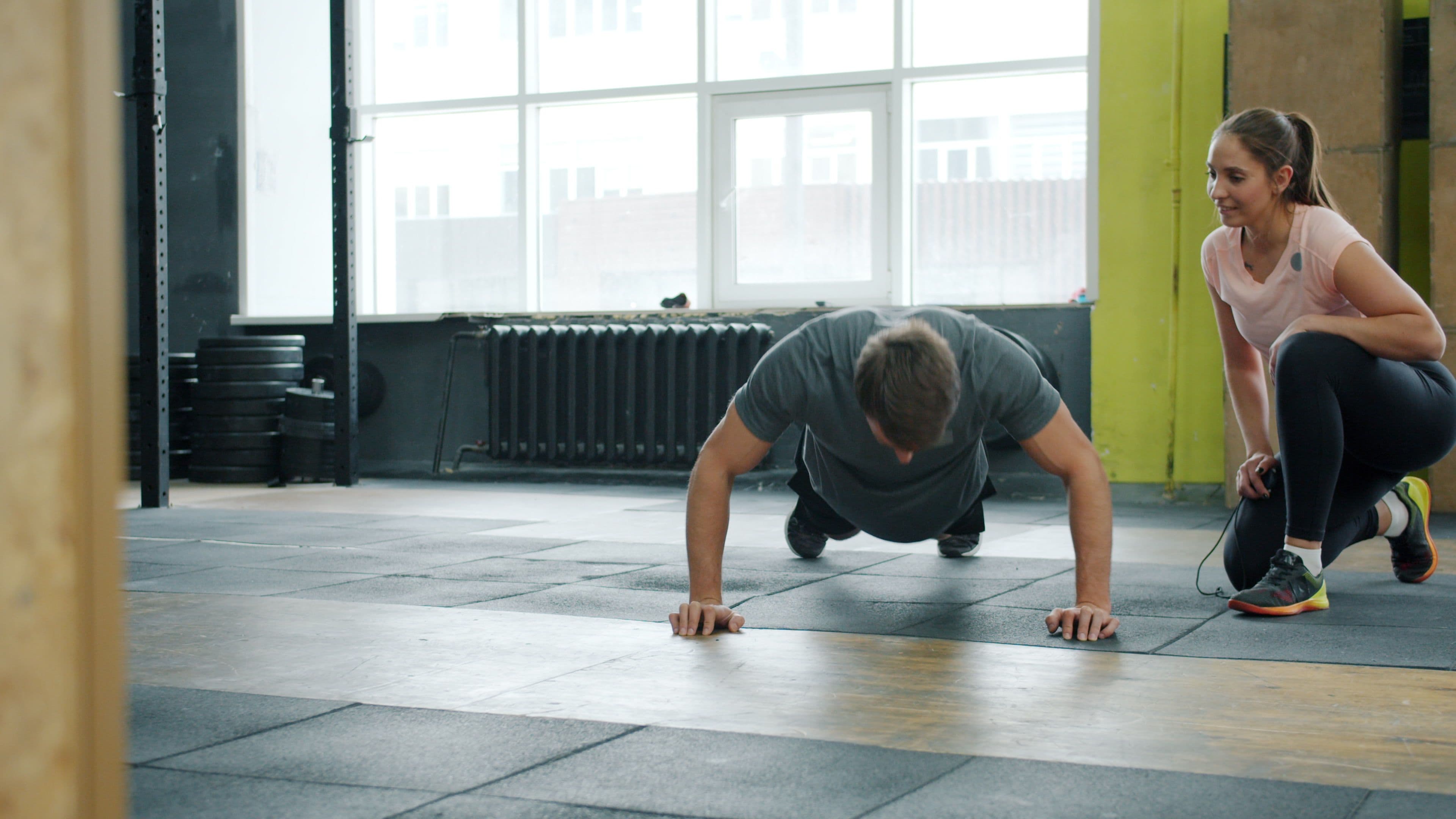 A personal trainer looking at a client who is performing a push up.