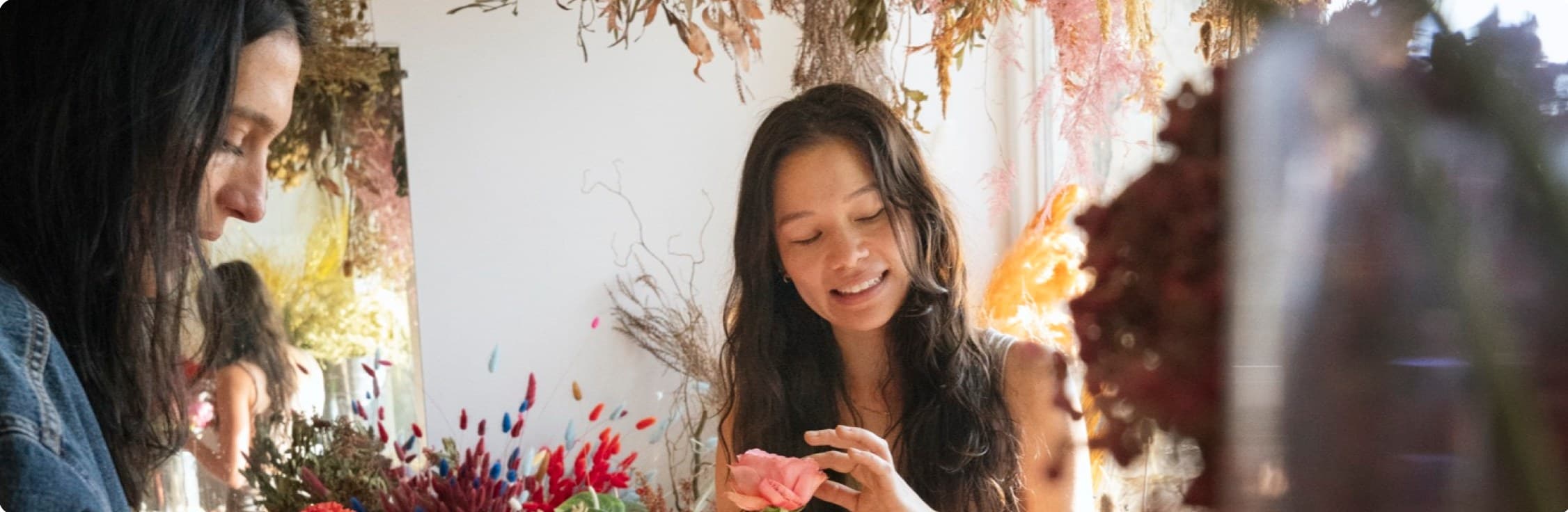 Two florists chatting while arranging dried flowers in their shop