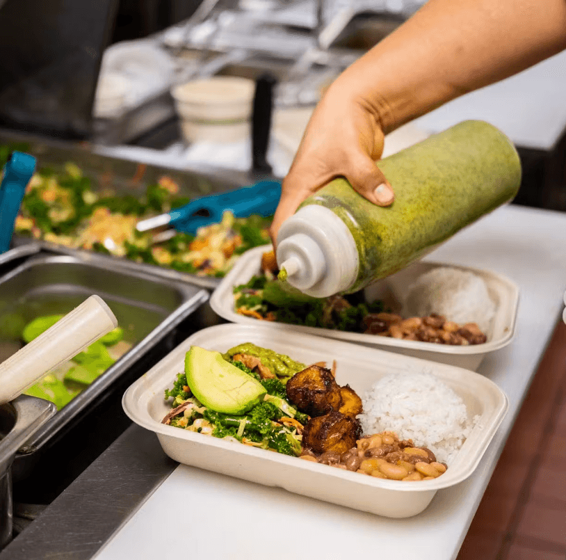 A Kitava Kitchen team member plating a to-go order in the restaurant.