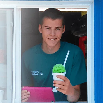 man holding a snow cone with an ordering device in hand