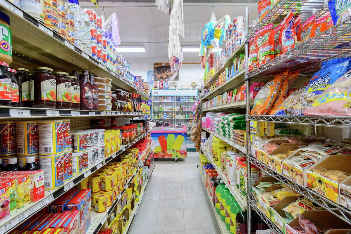 A grocery store aisle stocked with various food products including canned goods, baking ingredients, snacks, and beverages.