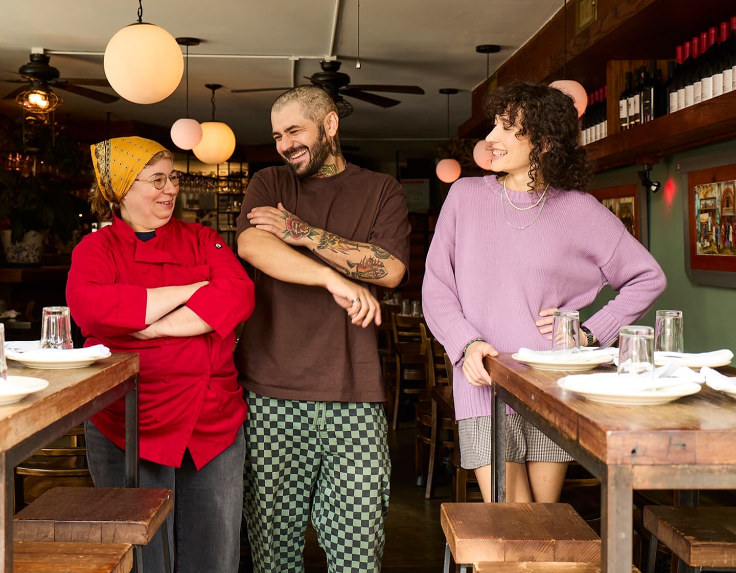 Two restaurant team members laughing together between tables.