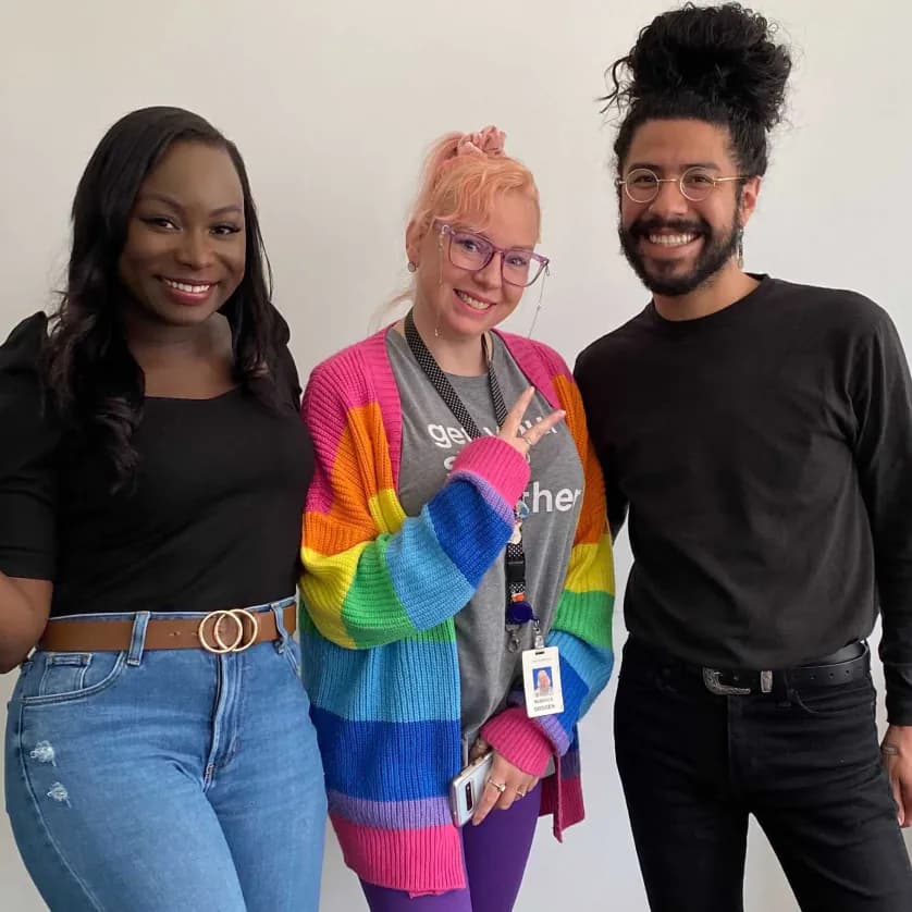 Team members smiling and posing in front of white wall
