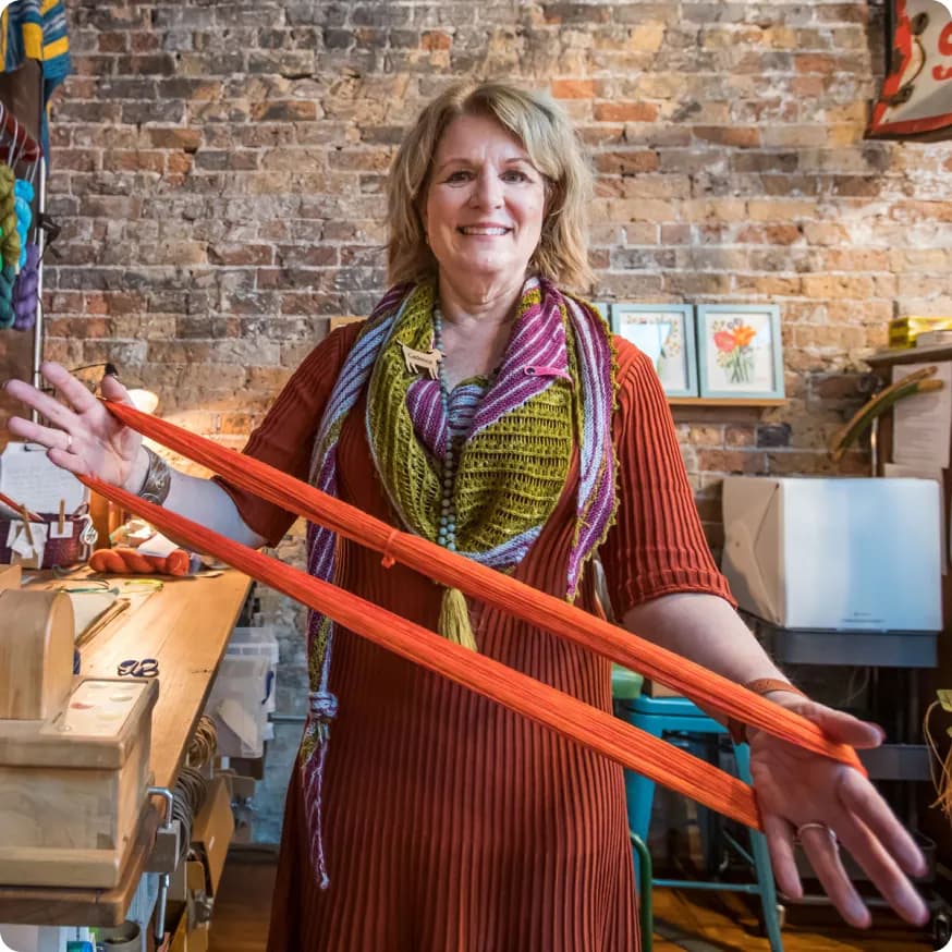 Lady in colorful orange outfit stretching an orange band