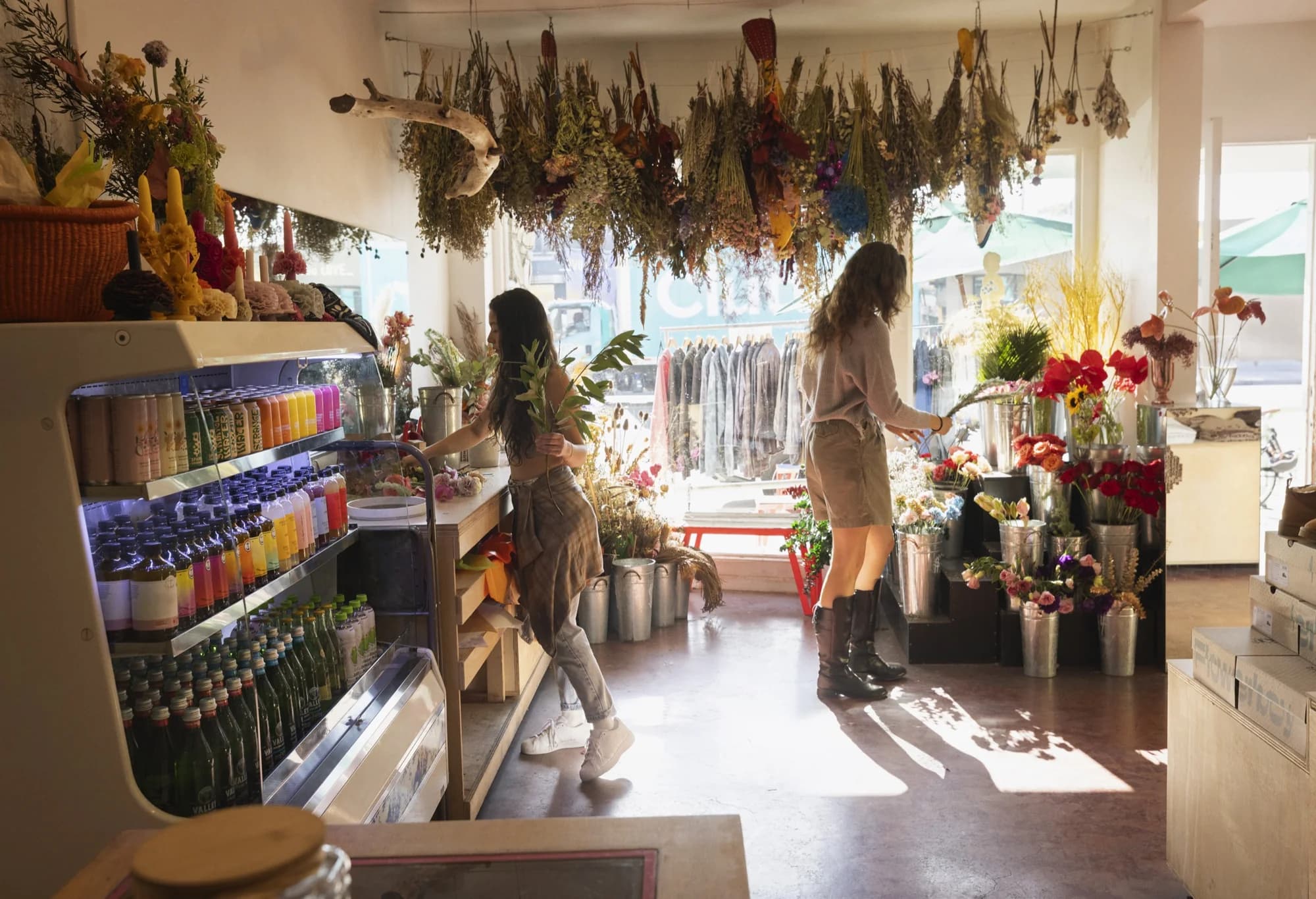 Two florists tending dried flowers and fresh bouquets in a sunlit flower shop