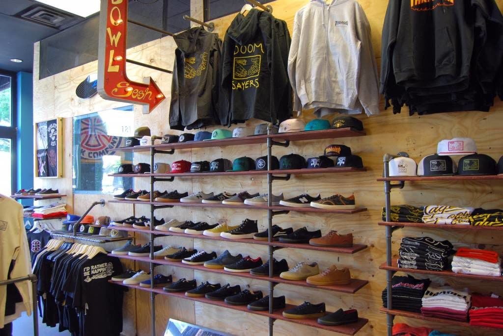 Hats and tops on shelves and racks in a clothing store.